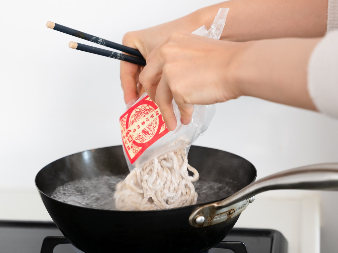 家庭の鍋へ和の個包装麺を入れる様子