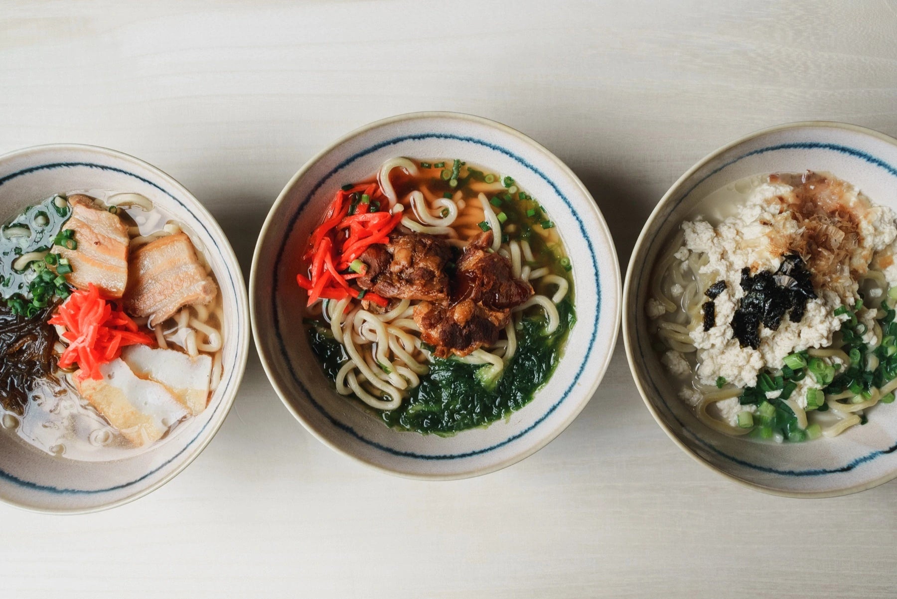 三枚肉そば、ソーキそば、ゆし豆腐そばが並ぶ和の食卓